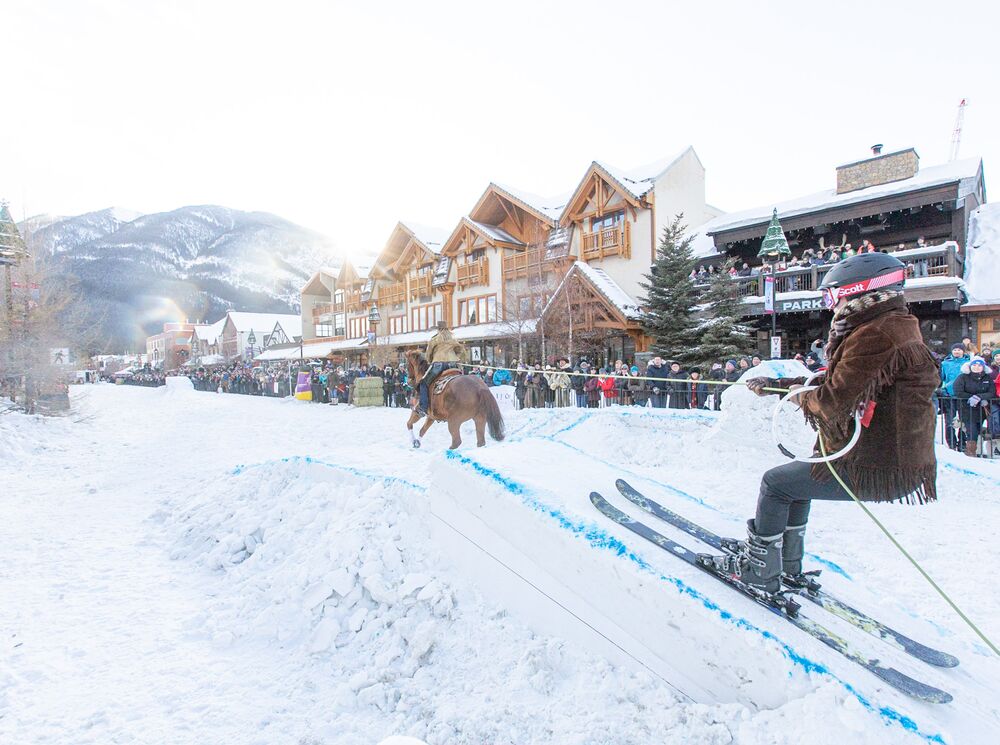 A skier performs a trick while being drawn by a horse during Snow Days Skijoring event on Banff Avenue