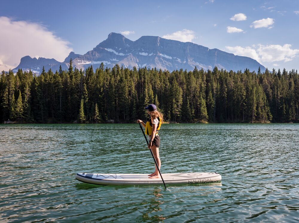 A paddle boarder on Johnson Lake with Mount Rundle in the background.