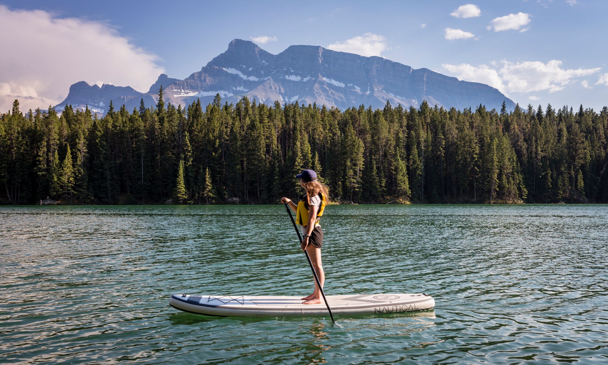 A paddle boarder on Johnson Lake with Mount Rundle in the background.