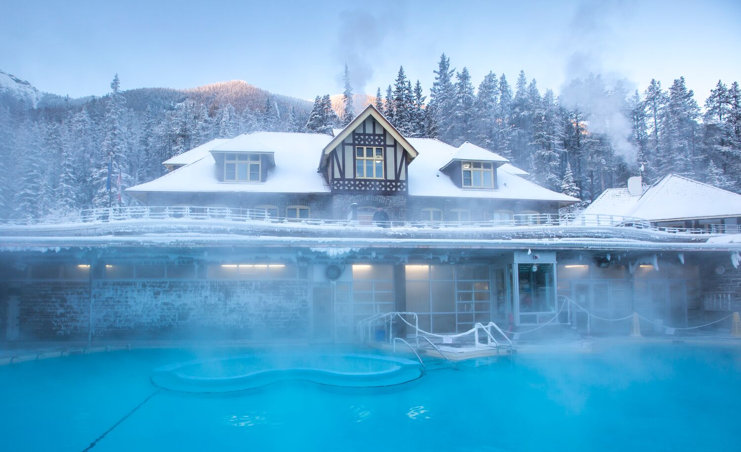 The exterior of the main bathhouse building at the Banff Upper Hot Springs covered in snow on a chilly winter day.
