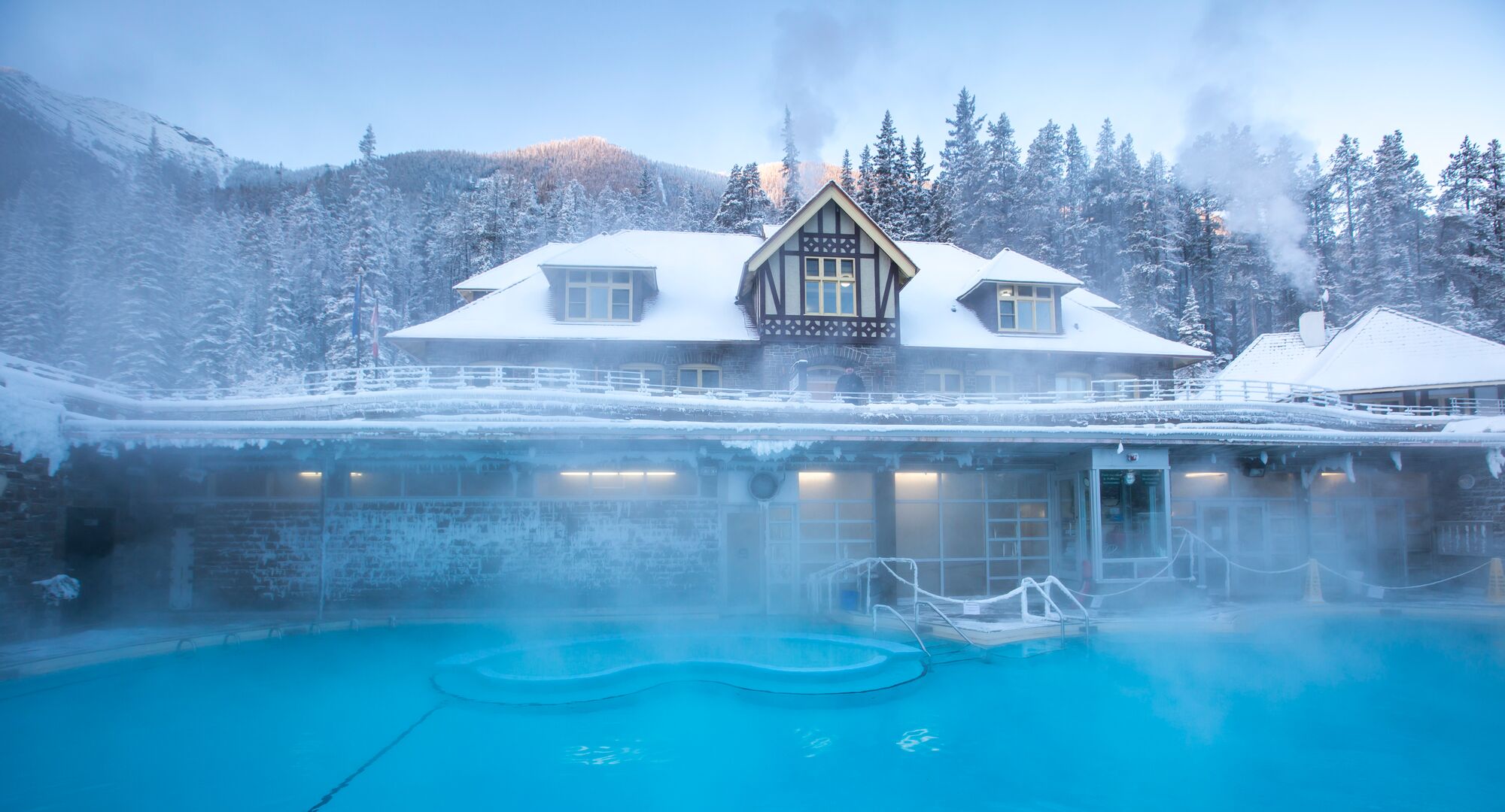 Visitors relaxing in Banff Upper Hot Springs with snow-covered mountains in the background