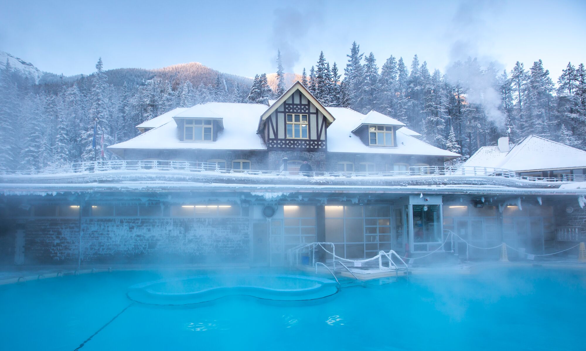 The exterior of the main bathhouse building at the Banff Upper Hot Springs covered in snow on a chilly winter day.