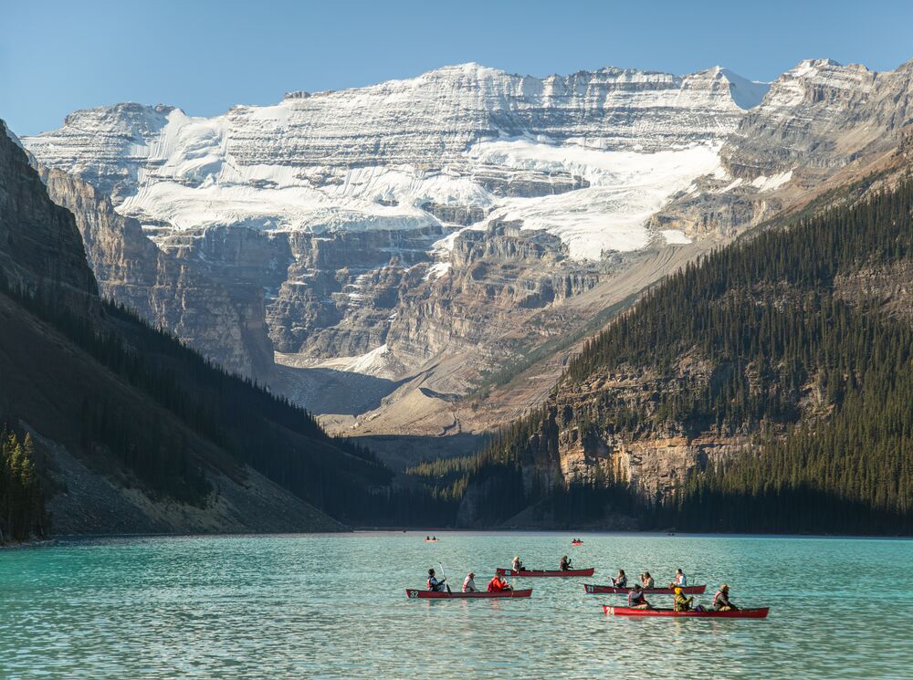 Canoes float on Lake Louise in Banff National Park on a blue bird day.