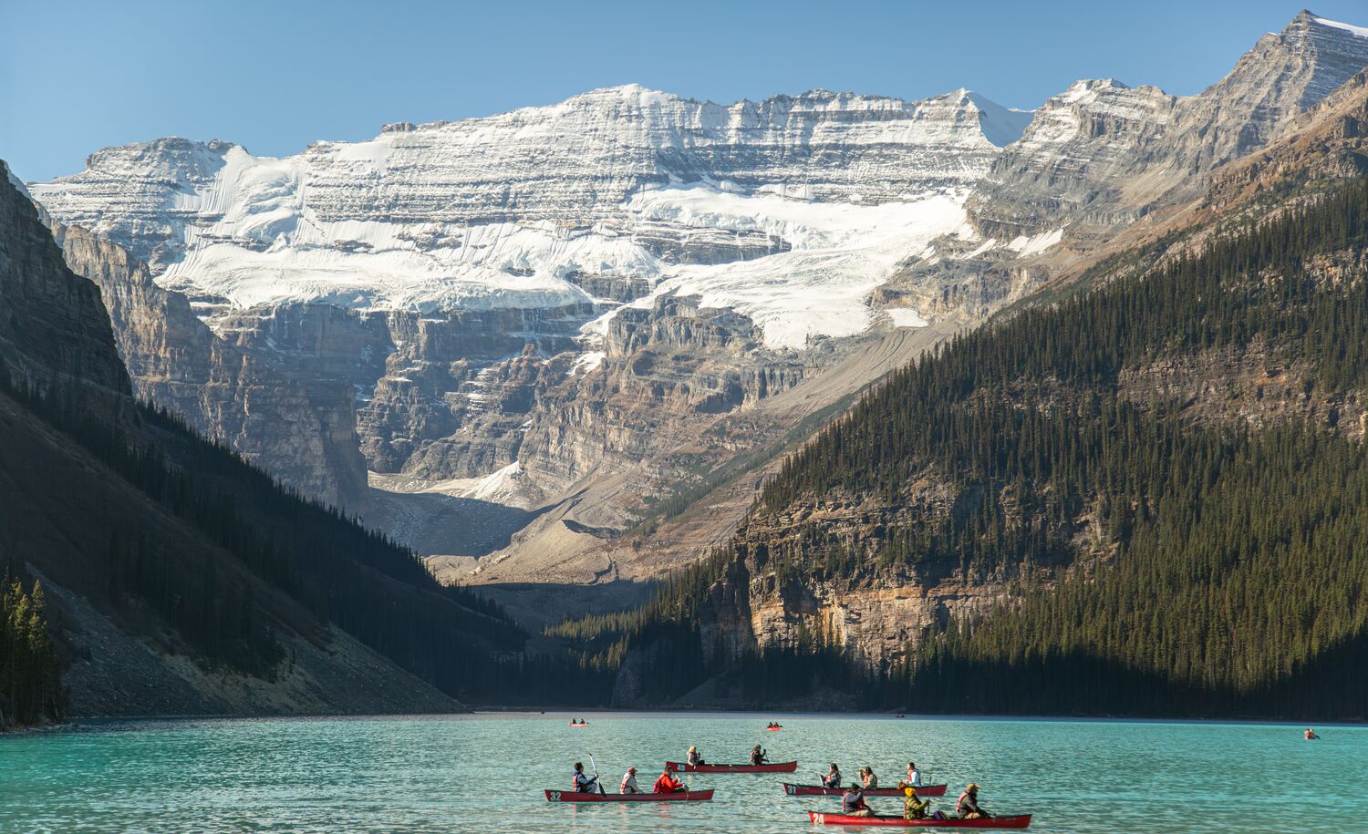 Canoes float on Lake Louise in Banff National Park on a blue bird day.