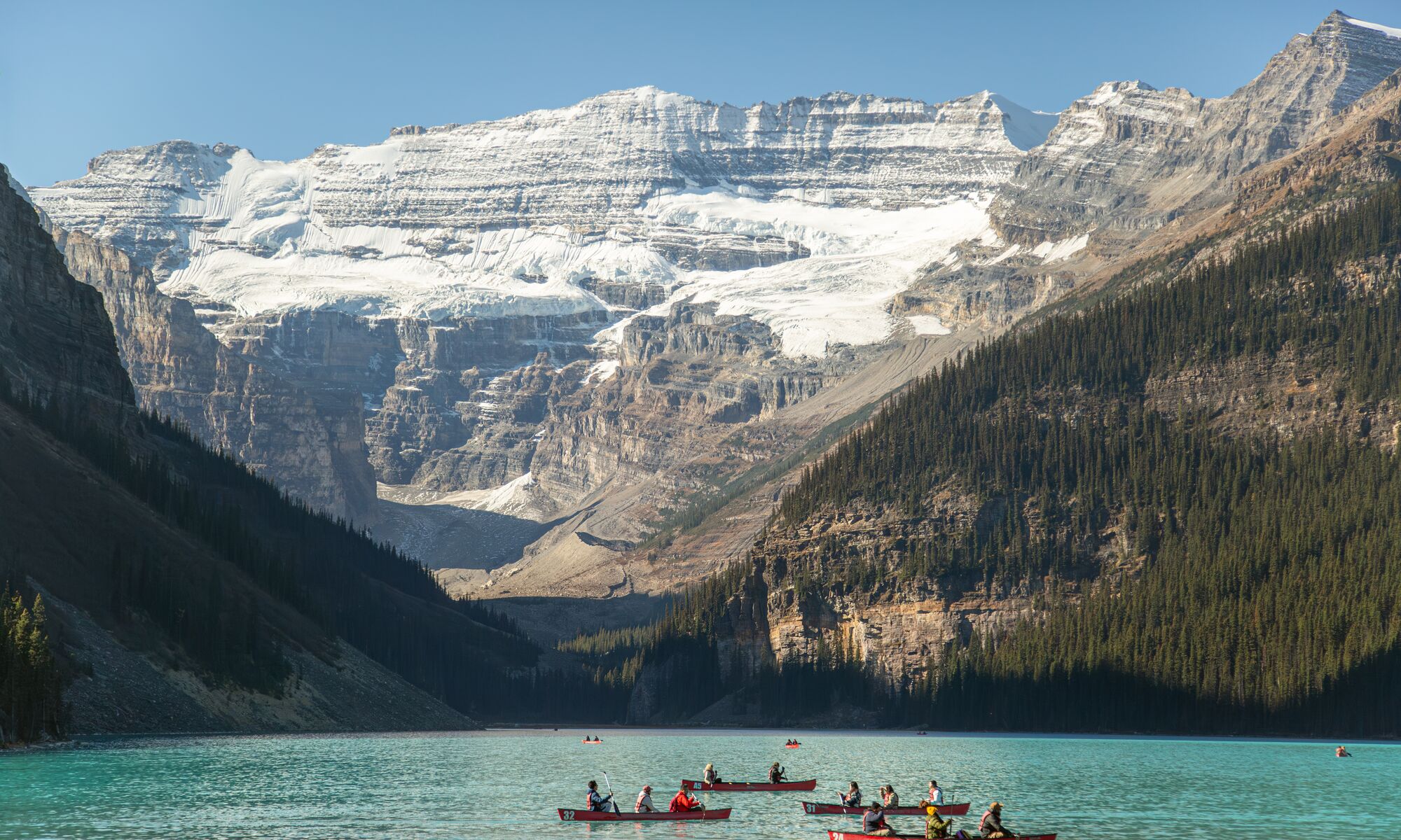 Canoes float on Lake Louise in Banff National Park on a blue bird day.