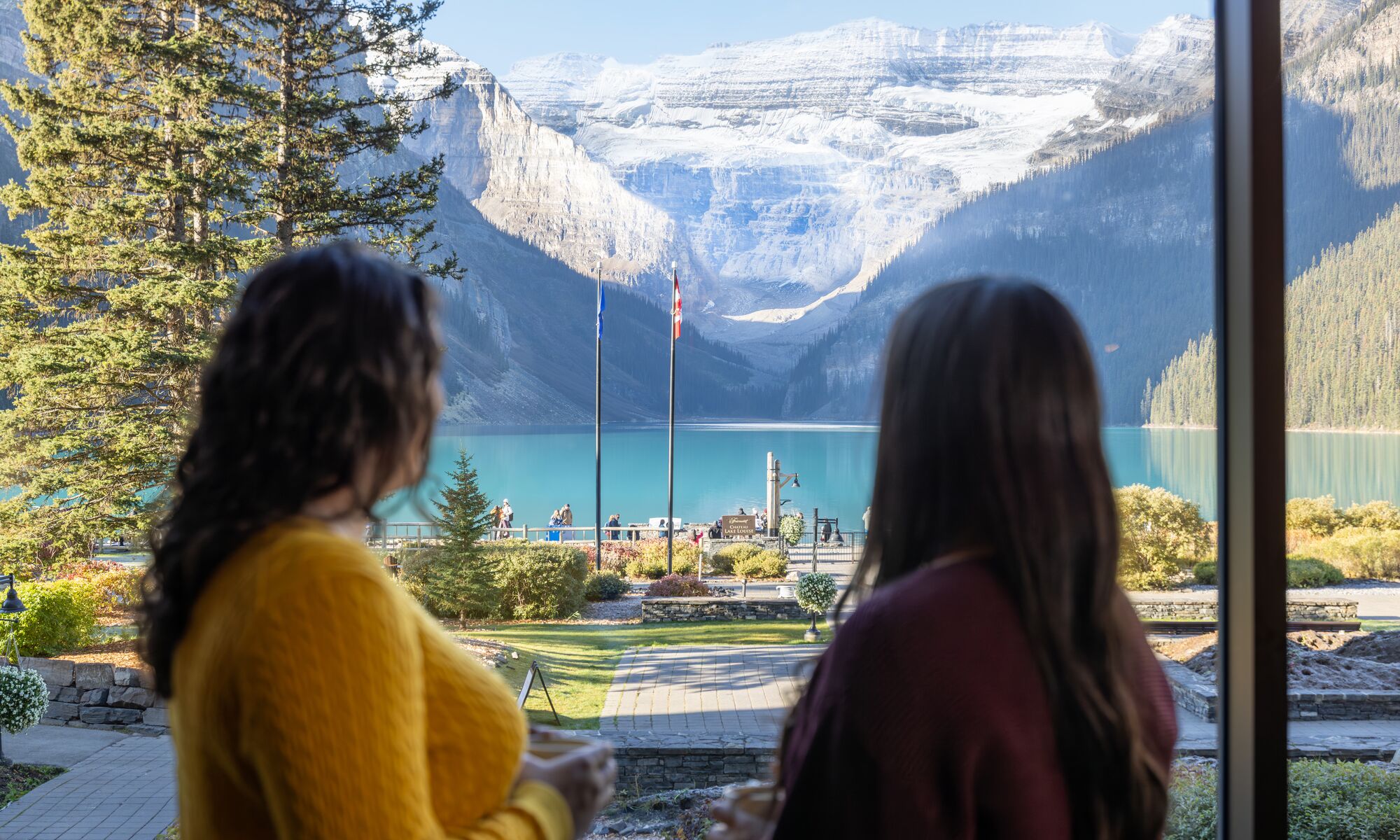 Two people look at the view of Lake Louise from the window of a restaurant that supports dietary restrictions at the Chateau Lake Louise in Banff National Park.